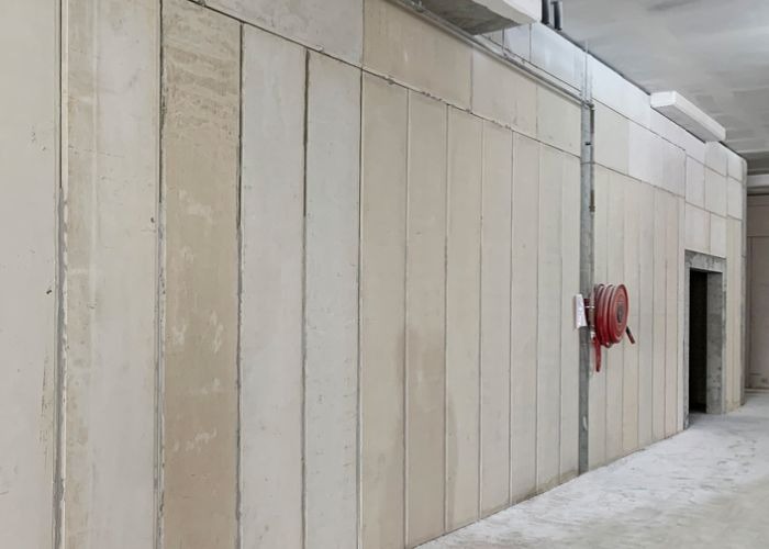 Bức tường bê tông trong nhà với cuộn vòi cứu hỏa màu đỏ, môi trường xây dựng hiện đại.