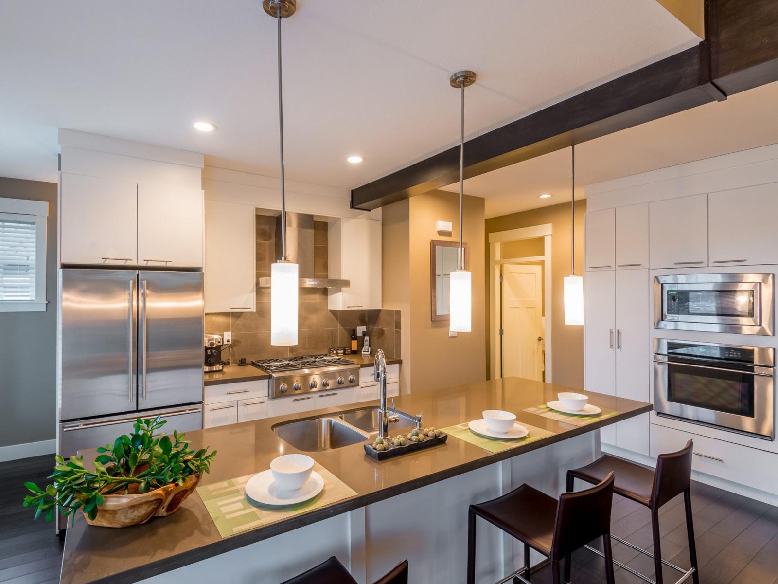 Nhà bếp hiện đại với quầy bar, đèn treo và thiết bị inox, không gian sáng sủa và thoải mái.