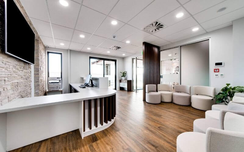 ve-sinh-khu-trung-van-phong-nha-khoa Phòng chờ văn phòng hiện đại với nội thất trắng, sàn gỗ và khu vực tiếp tân sang trọng.