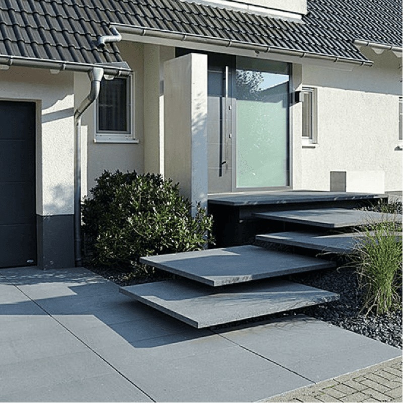 xay-dung-can-than-va-dung-ky-thuat Lối vào nhà với bậc thang hiện đại bằng đá, cửa kính lớn, cây xanh tạo phong cách tối giản.