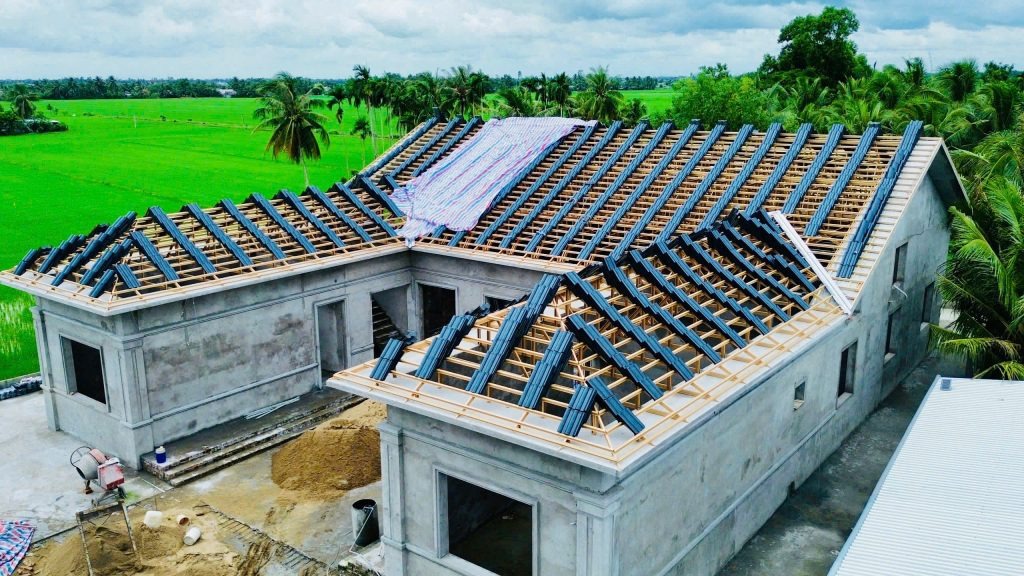 xay-lai-mai-nha-co-can-cap-phep-khong-2 Nhà đang xây dựng, mái nhà đã lợp một phần, xung quanh là cánh đồng lúa, bầu trời mây xanh.
