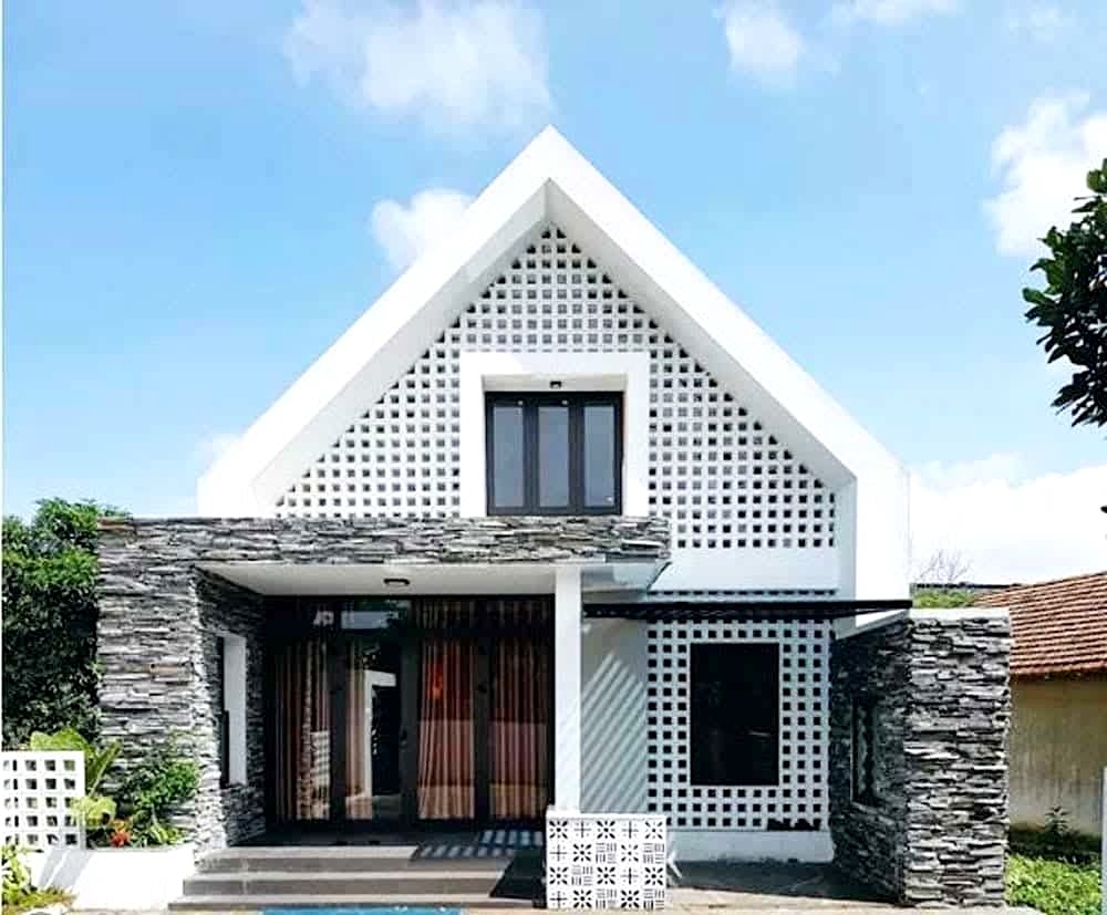 Nhà phố hiện đại với mái dốc và tường ốp đá giữa không gian thoáng đãng, bầu trời xanh.