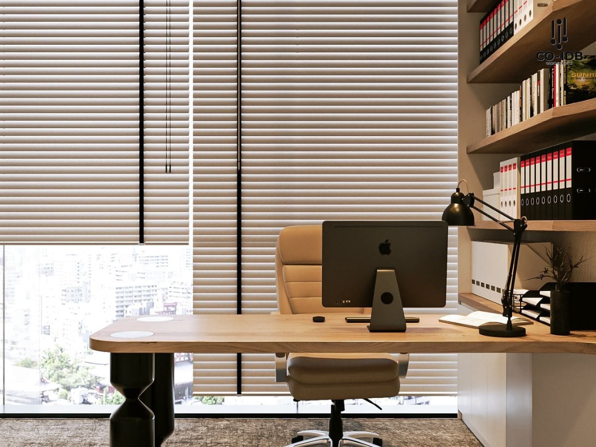 Văn phòng hiện đại với bàn làm việc gỗ, máy tính và kệ sách. Không gian thoáng đãng với rèm che lớn.