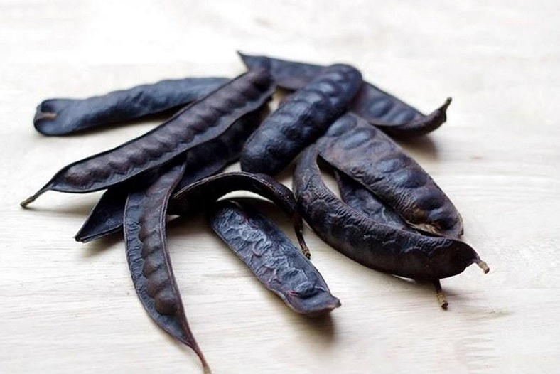 Hình ảnh quả bồ kết khô trên nền gỗ nhạt, được dùng trong y học và chăm sóc tóc.