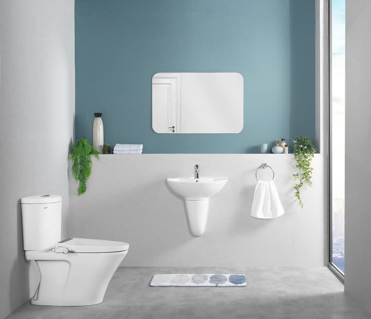 Phòng tắm hiện đại với tường xanh, bồn cầu, bồn rửa, gương và cây xanh trang trí.