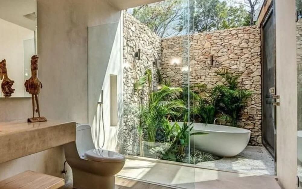 Phòng tắm sang trọng với bồn tắm ngoài trời, cây xanh và tường đá tự nhiên.
