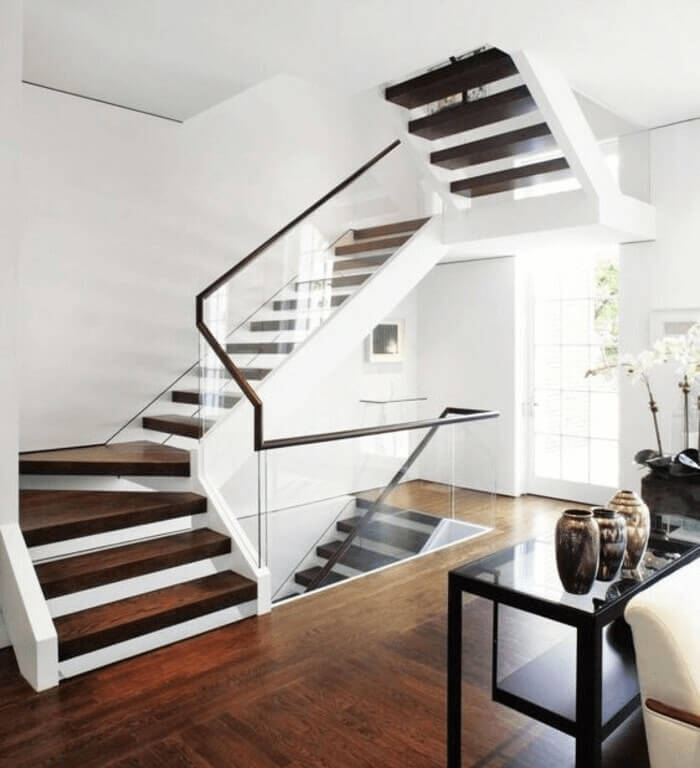 Cầu thang hiện đại với tay vịn kính trong suốt, nền gỗ tối màu, phong cách tối giản, ánh sáng tự nhiên.