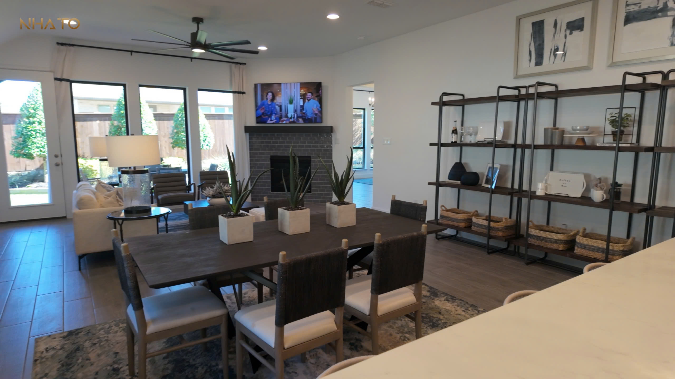 z6803397537011_b6f0b48438df9b104041468071a847dc-1-1 Phòng khách hiện đại với bàn ăn lớn, đèn trần, tivi treo tường, và cửa sổ tràn ánh sáng tự nhiên.