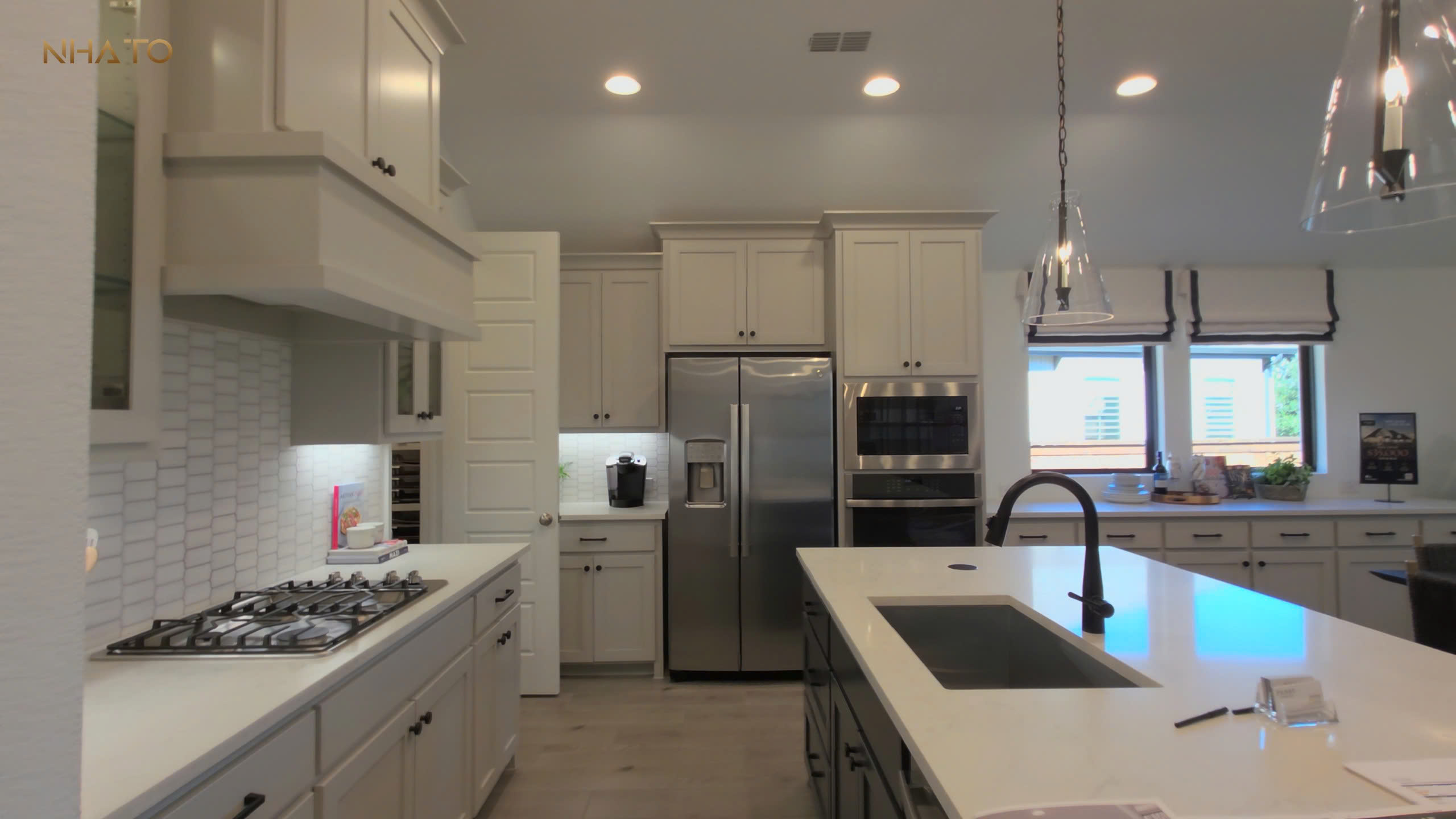 z6803397537014_5c2893cf61568d2a2c8eb437169d6b6d-1 Nhà bếp hiện đại với tủ trắng, bếp ga, tủ lạnh inox và quầy bếp đá cẩm thạch sáng.