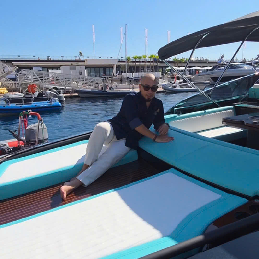 Người đàn ông thư giãn trên du thuyền sang trọng tại bến cảng, trời nắng và xanh.