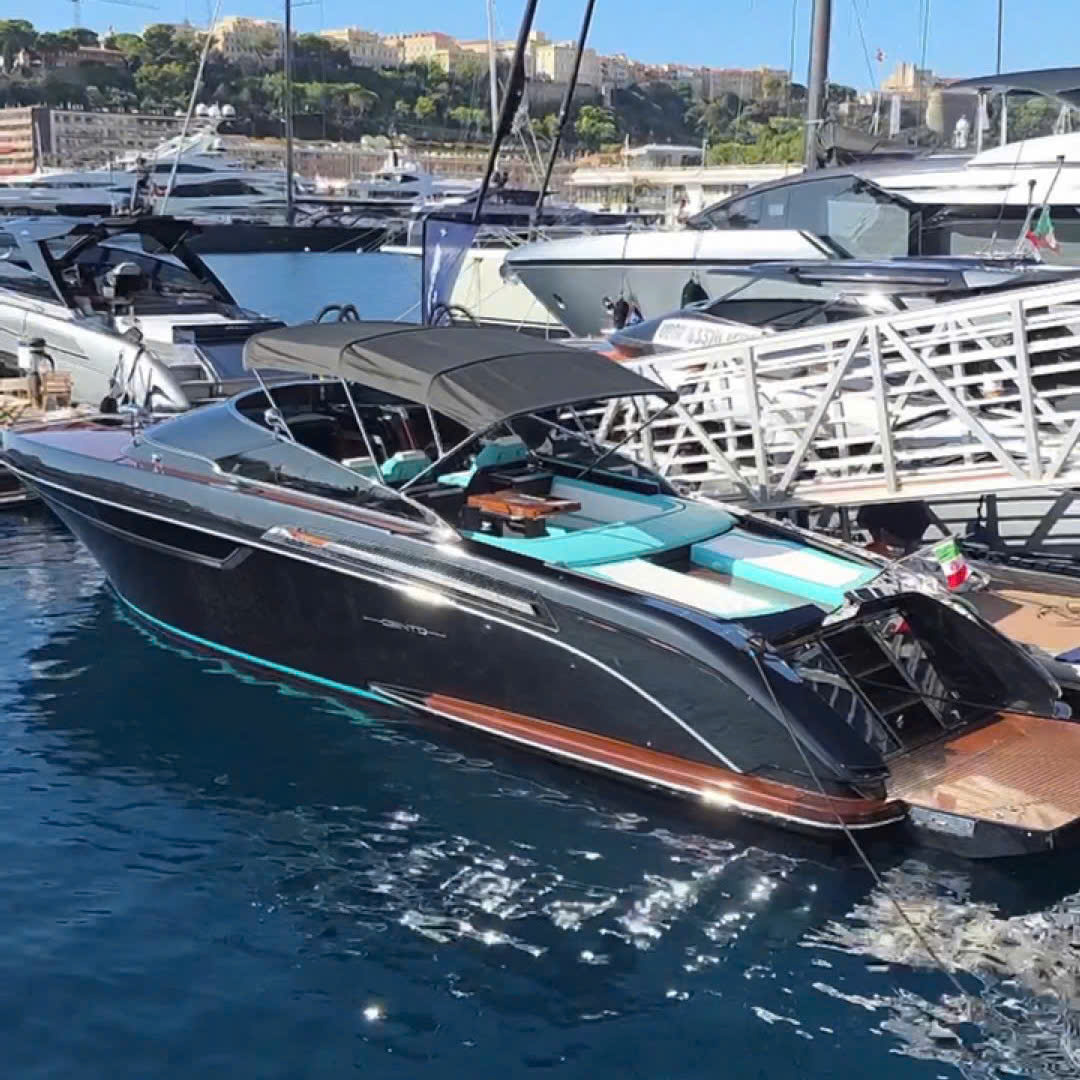 Du thuyền sang trọng neo đậu tại bến cảng, nền trời xanh và kiến trúc ven biển sườn đồi.