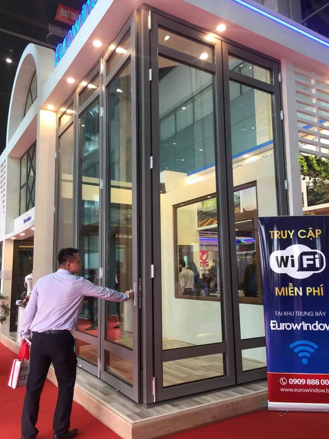 Người đàn ông mở cửa tại gian hàng Eurowindow, có biển báo WiFi miễn phí tại triển lãm.